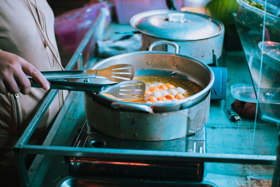 Close-up of a person frying food in a pan using tongs on a stove indoors.