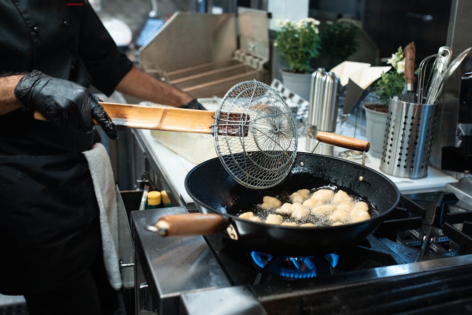 A chef fries dumplings in a commercial kitchen setup, showcasing culinary skills.
