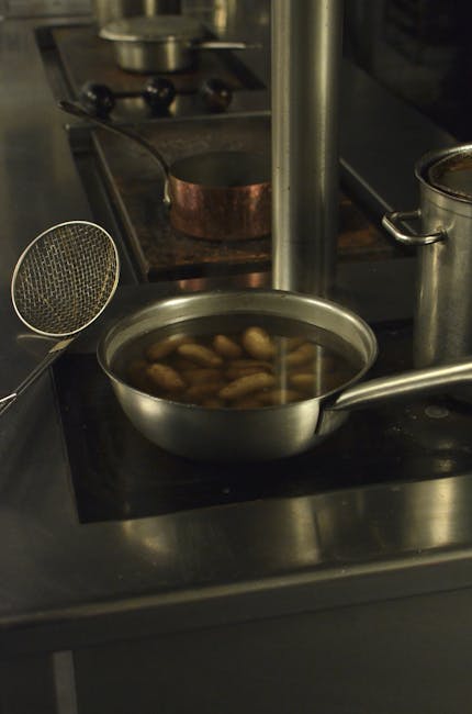 Stainless steel pot with peanuts boiling on a modern kitchen stove.