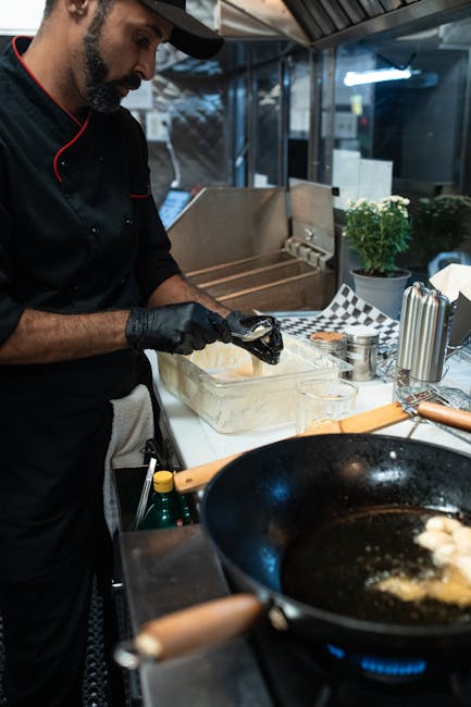 Chef skillfully cooking in a modern kitchen with frying pan and ingredients.
