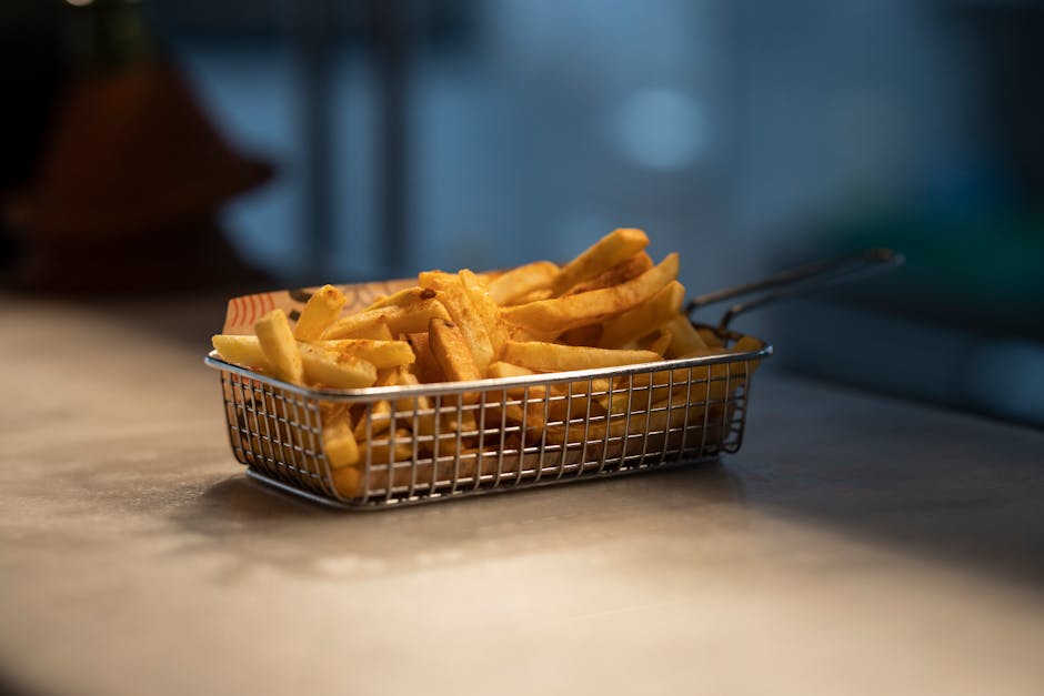 Delicious golden fries served in a steel basket on a table. Perfect for food photography.