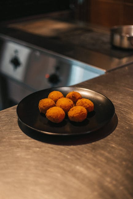 A mouth-watering close-up of golden arancini on a sleek black plate, ready to savor.