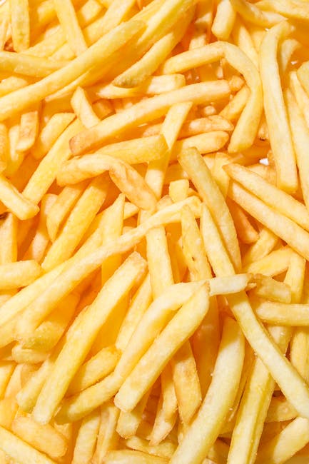 A close-up of delicious crispy French fries with a vibrant yellow background.