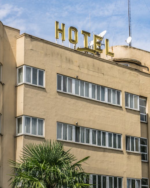 Historic hotel exterior with prominent signage and palm tree in urban setting.