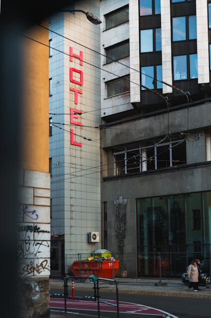 Street view of a city hotel with a prominent neon red sign, urban setting.