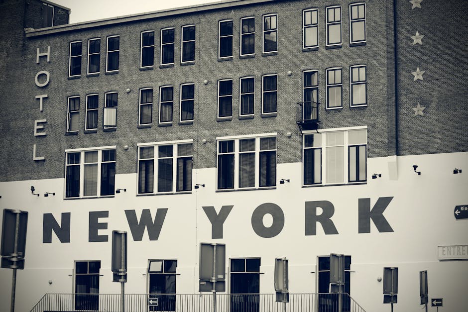 Black and white photo of a hotel facade with 'New York' signage, showcasing urban architecture.