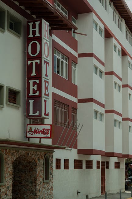 Urban hotel facade with a prominent red and white sign, ideal for lodging themes.
