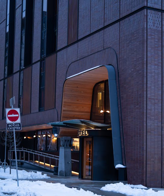 Stylish modern hotel entrance with snow-covered streets in Toronto, showcasing architectural design and warm lighting.