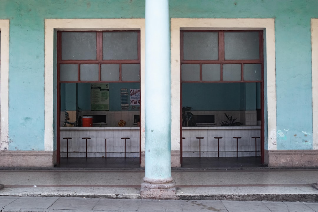 a blue building with two windows and a bench in front of it
