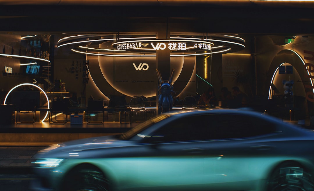 A blue car driving past a store front