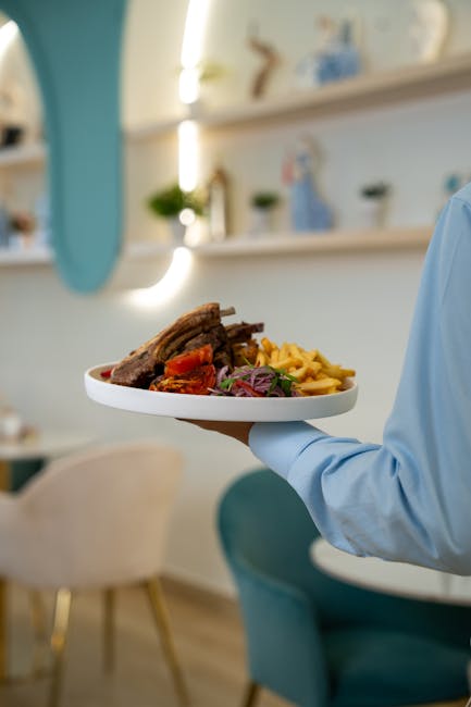 Close-up of gourmet meal with ribs and fries on a white plate in a stylish restaurant setting.