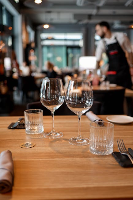 A beautifully arranged table with glasses and cutlery in a stylish modern restaurant.
