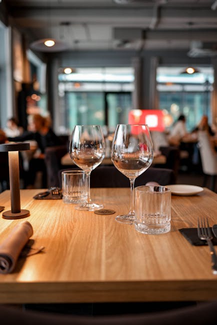 A beautifully set restaurant table with glasses and napkins in a modern indoor setting.