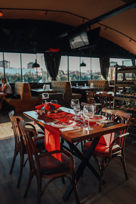 Elegant dining setup with wine glasses and red decorations in a modern restaurant setting.