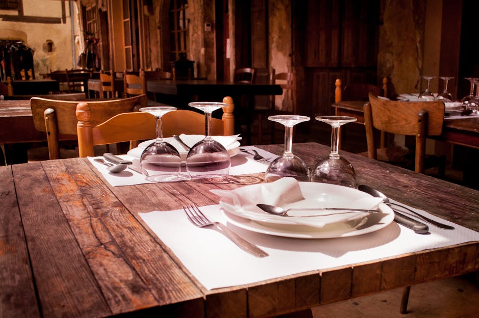 A rustic restaurant table set with wine glasses and cutlery invites guests to dine.