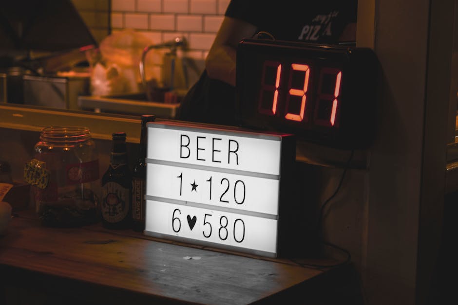 Indoor scene of a beer price sign and digital light in dimly lit setting.