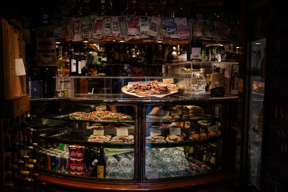 Warm and inviting Italian cafe with a variety of pizzas and drinks displayed on a counter.