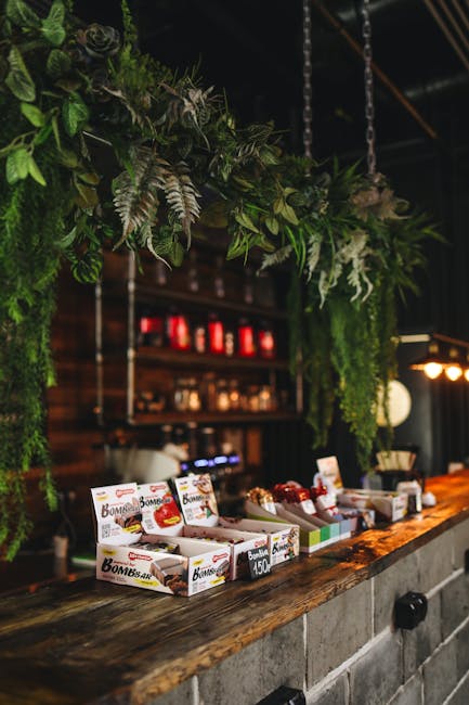 A beautifully styled rustic café interior featuring a wooden counter, snacks, and greenery.