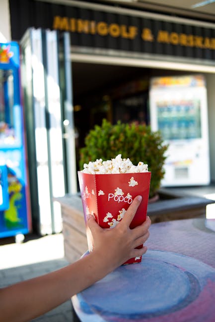 Person holding popcorn at an outdoor minigolf and snackbar location.