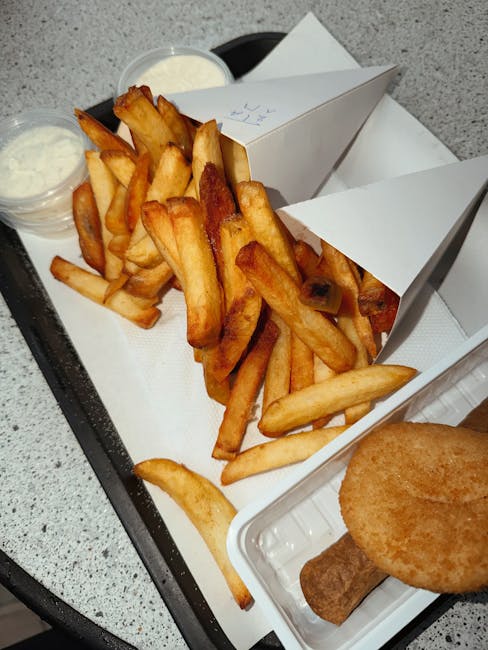 Tasty french fries served on a tray with sauces and croquettes.