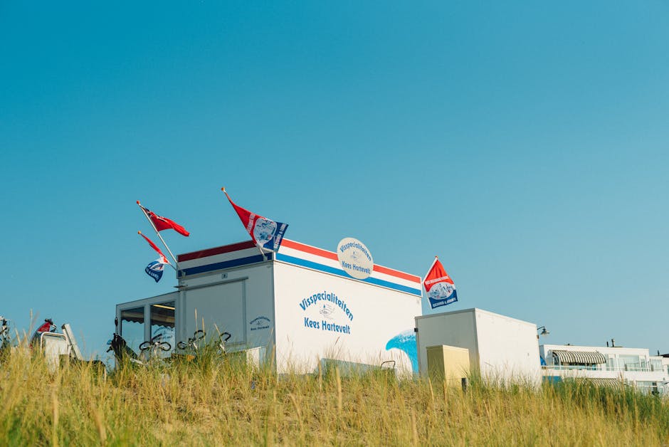 Outdoor view of a beachside shop in Holland under a bright blue sky, featuring flags.