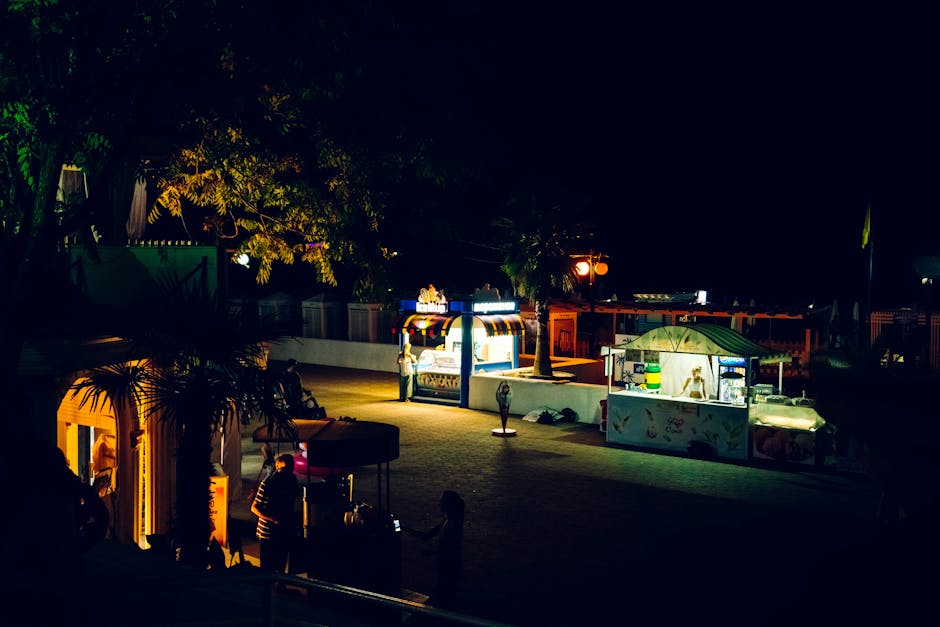 A vibrant night scene featuring illuminated food stalls on a street in Sochi, Russia.