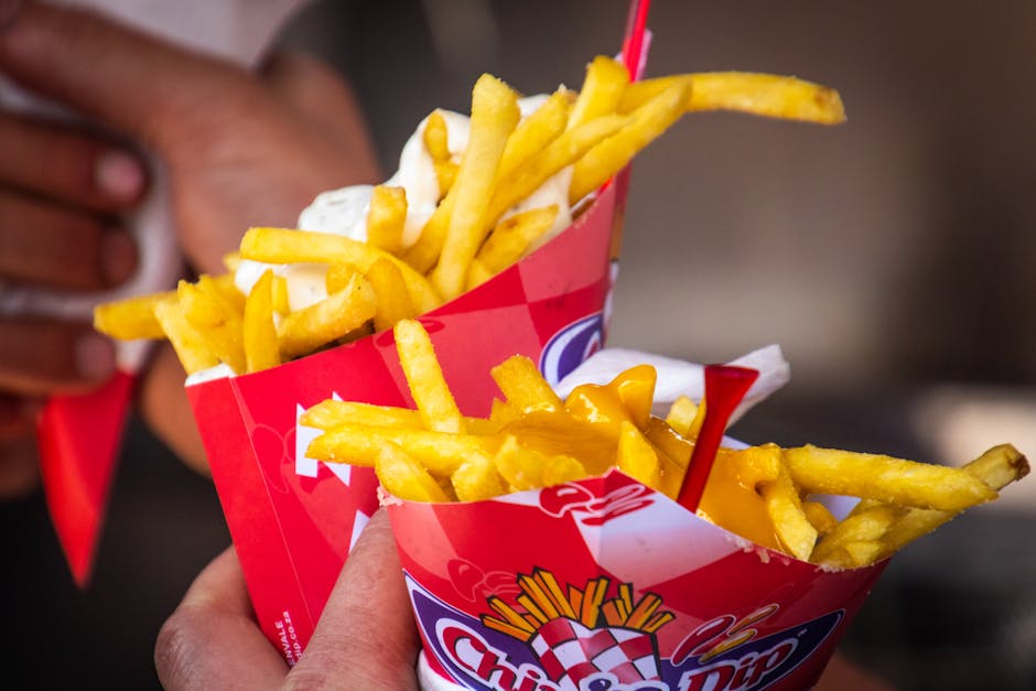 Tasty cheese-covered french fries held closely. Perfect fast food delight.