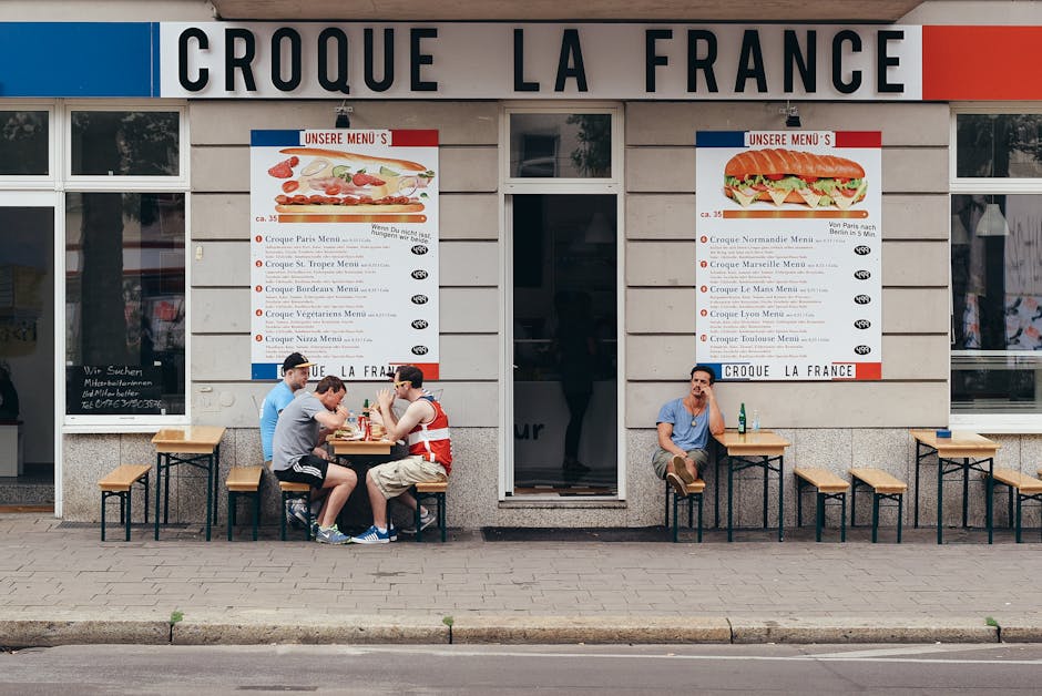 Outdoor seating at a French bistro with people enjoying food and drinks in an urban setting.