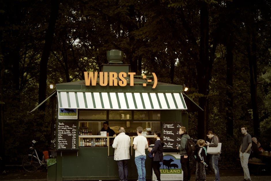 Charming outdoor kiosk serving Wurst with people queuing on a sunny day.