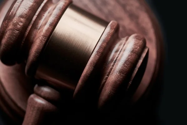 Een close-up van een houten hamer met een metalen band, symbolisch voor rechtspraak en juridische zaken.