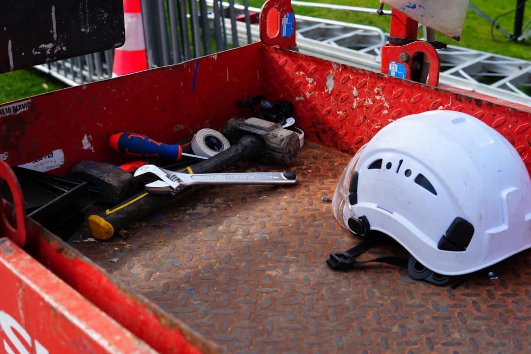 A white hard hat and various construction tools inside a red metal container