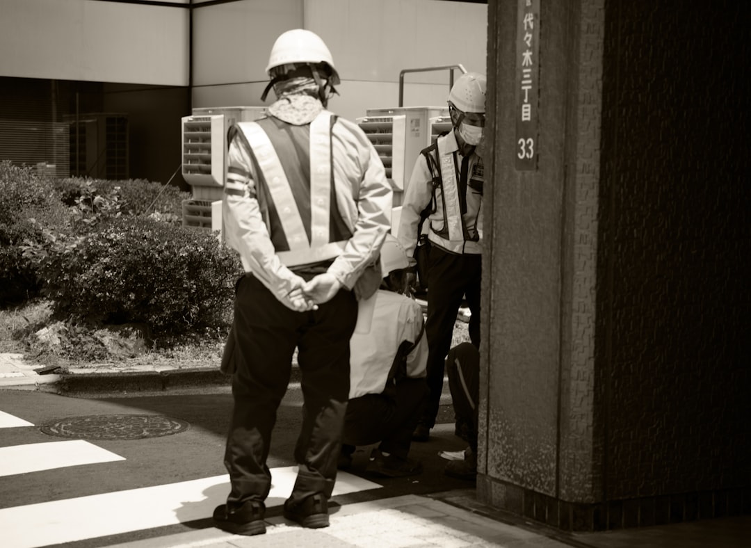 Two men wearing reflective vests and hard hats outside