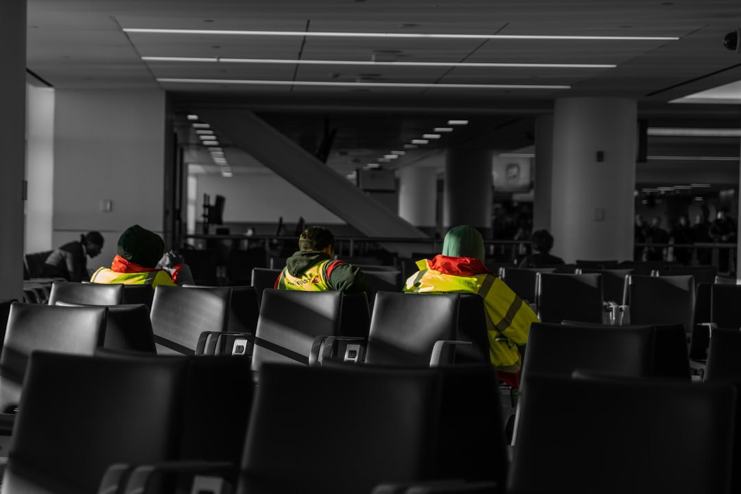 Three people in yellow vests sit in airport chairs